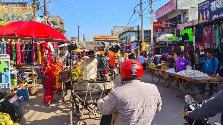 Shops are set up on the road, e-rickshaws are parked in front of the police station