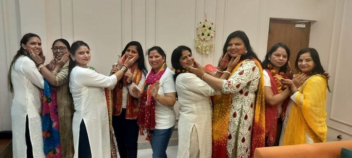 Women associated with social organizations started Holi by applying Tilak