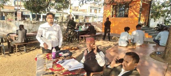 पेड़ की छांव के नीचे बैठकर विधि कार्य करते अधिवक्ता