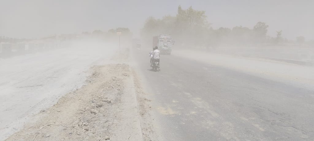 Road riddled with potholes, clouds of dust flying