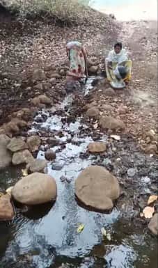 गंदे झिरिया से पानी पीते हुए ग्रामीण