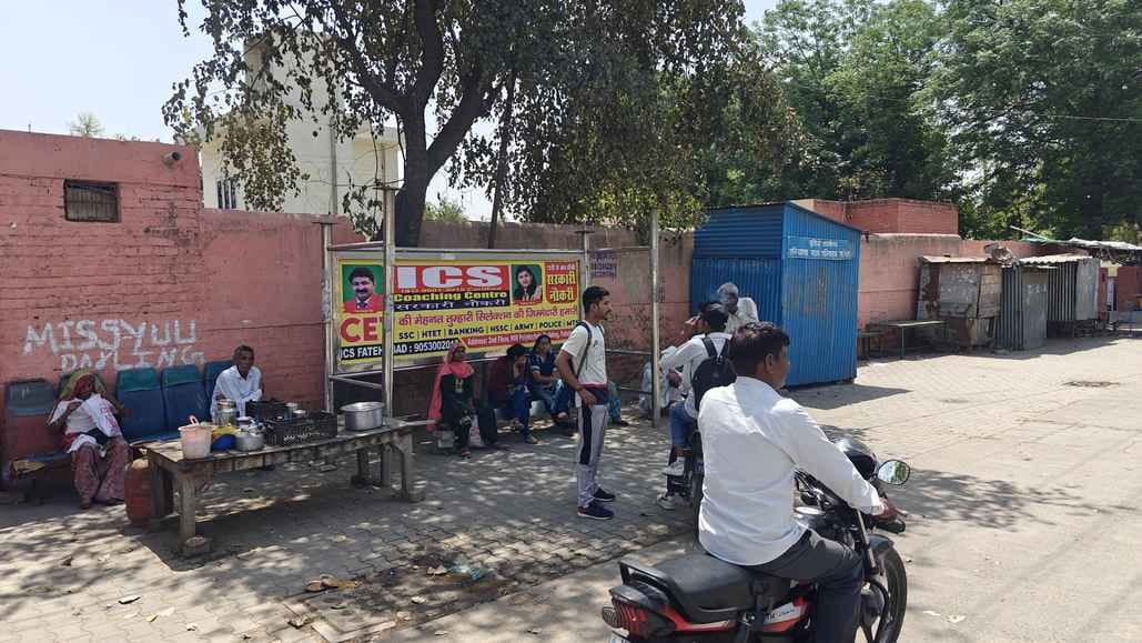 Passengers are forced to wait for the bus under a broken shelter