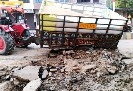 A tractor-trolley loaded with wheat got stuck in a dug up road pit