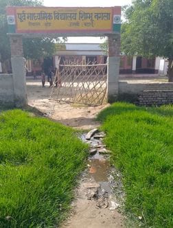 School children cross the drain water filled on the road