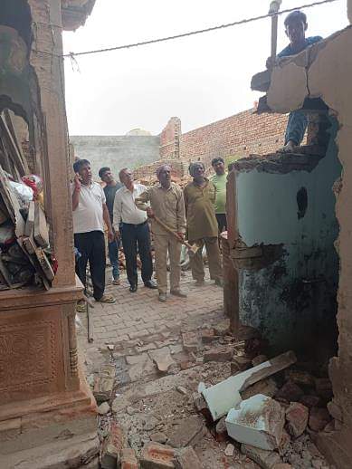 अवैध रूप से बनें शौचालय को तोड़ते नगर पालिका  कर्मचारी। 