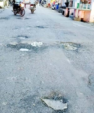 Traders and passersby are troubled by deep potholes on the main road