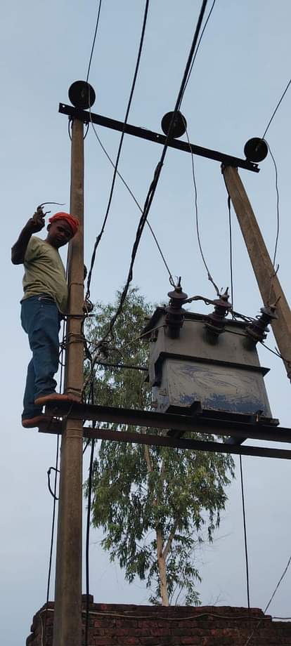  ट्रांसफार्मर पर तार को ठीक करता कर्मी। 