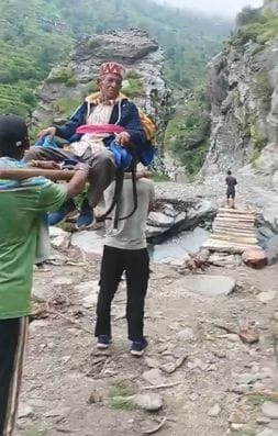 The elderly man was taken to the road with the help of wooden sticks on a chair
