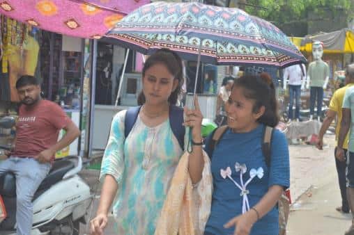 मथुरा गर्मी में छाता लगाकर जाती युवतियां।