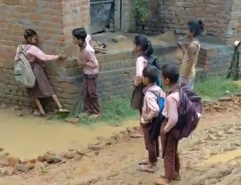 Student reaching school by keeping his feet in mud