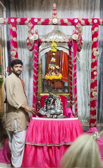 The King of Kings is seated in a pink velvet swing, devotees keep gazing at him with bated breath
