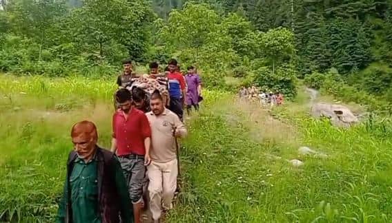 युवक को कंधों पर उठा कर सड़क की तरफ ले जाते लोग।