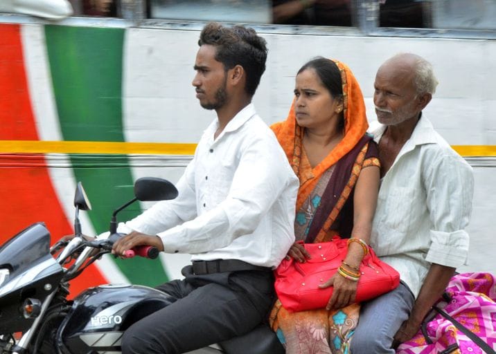 Three passengers are riding fast without helmets