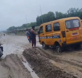 School van stuck in the mud on the service road, traffic jam