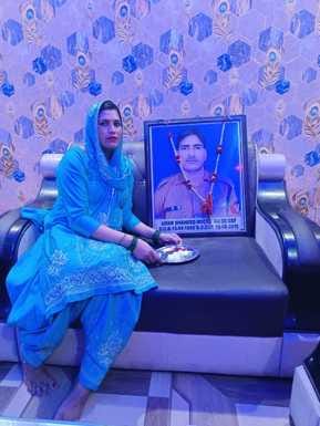 Neha is celebrating Rakshabandhan by tying a Rakhi on the picture of her martyred brother