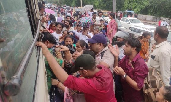 Passengers struggling to board the bus to reach their destination.