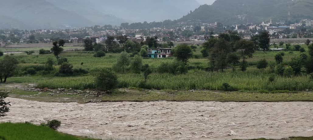 पुंछ में पुलत्स्य नदी की धारा के उस पार खेतों में  बने मकान जिसमें 30 लोग फंसे हुए हैं। संवाद