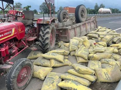 फोटो 24 एयूआरपी 09 हाईवे पर पलटी ट्राली व पड़ीं सीमेंट की बोरियां। संवाद