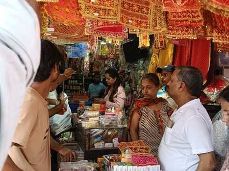 Crowds gathered at shops selling puja materials and decorative items in the market.