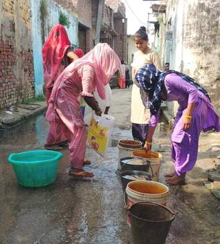 बनियाठेर के गांव मानकपुर नरौली में पन्नी से बाल्टी भरती महिला - संवाद