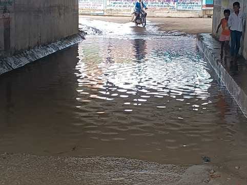 Railway underpass filled with water, pedestrians wading through three feet of water