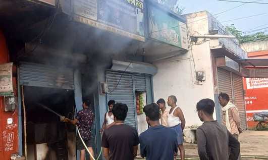 दुकान में लगी आग बुझाते लोग।