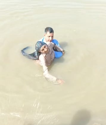 An elderly woman fell into the Yamuna River after collapsing; her son jumped in to save her.