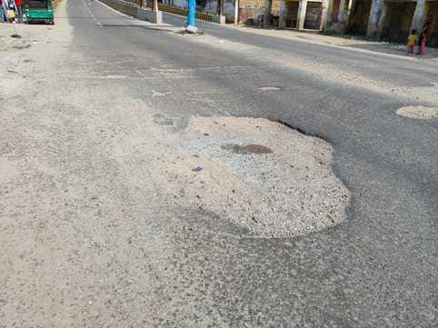 Potholes near the overbridge pose a risk of accidents.