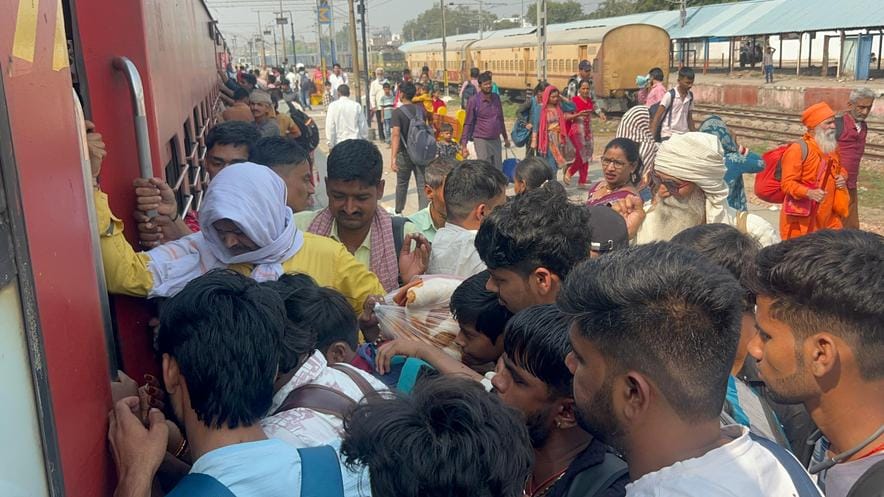 Trains are packed to capacity, with passengers hanging onto the doors.