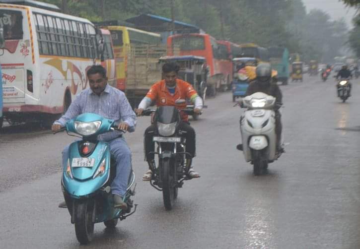 फोटो-14- घंटाघर रोड पर बारिश में भीगते जाते बाइक सवार। संवाद