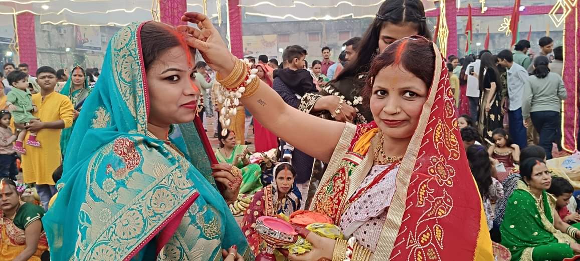 नगर के रामलीला मैदान स्थित घाट पर एक दूसरे को सिंदूर लगाती व्रती महिला।संवाद