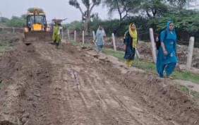 अहिल्यागंज परिक्रमा मार्ग पर कार्य करती जेसीबी के बराबर से निकलते श्रद्धाल।