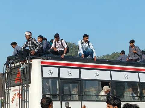 Due to the shortage of buses, passengers are risking their lives by travelling on the rooftops