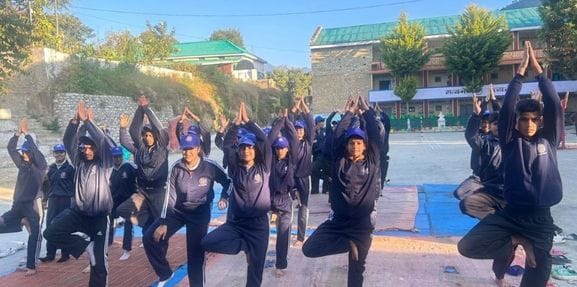 Volunteers learn the intricacies of yoga at Nirmand School