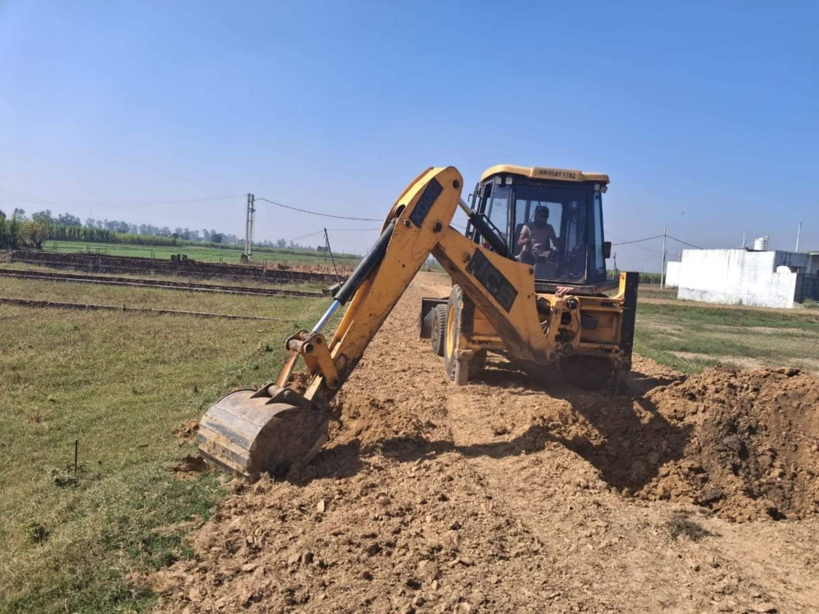 अवैध कॉलोनी में बनी सड़क को तोड़ती जेसीबी। डीआईपीआरओ