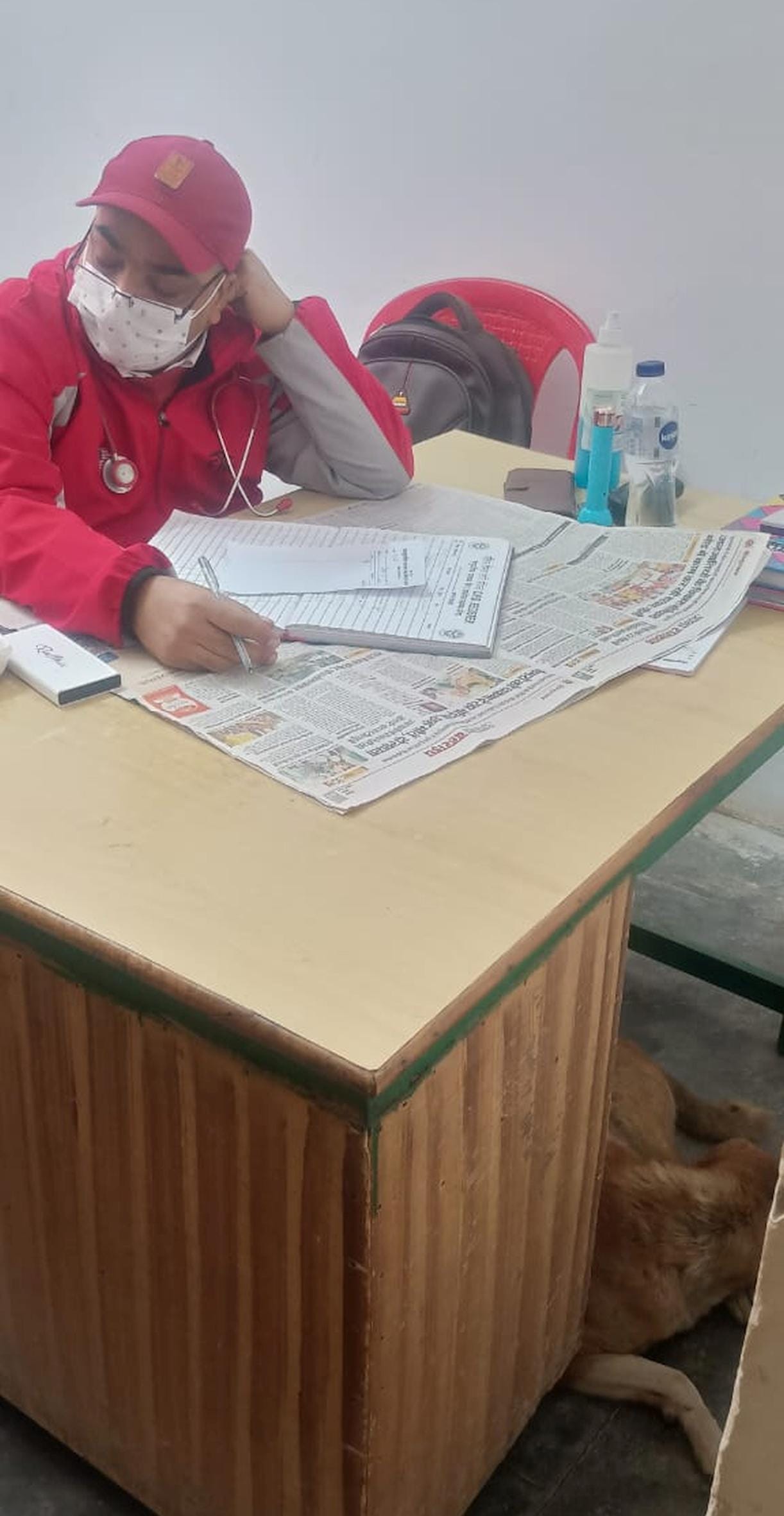 The dog sits under the doctor's table, treating patients.
