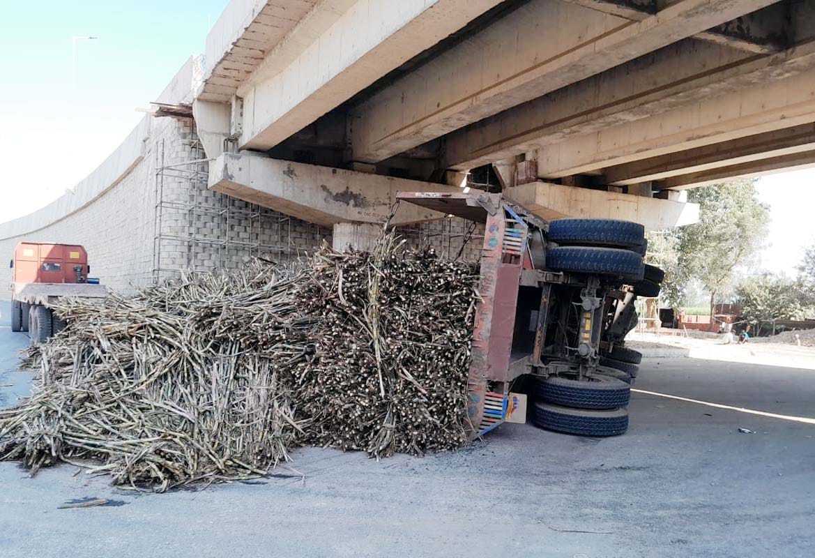 A truck loaded with sugarcane overturned under an overbridge in Khutar, narrowly avoiding an accident.