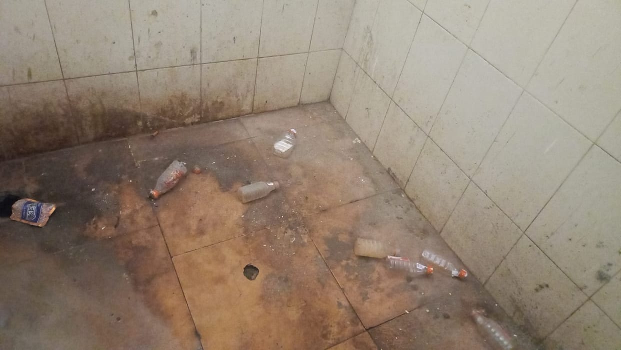 Stones are visible outside the toilets, liquor bottles are lying inside.