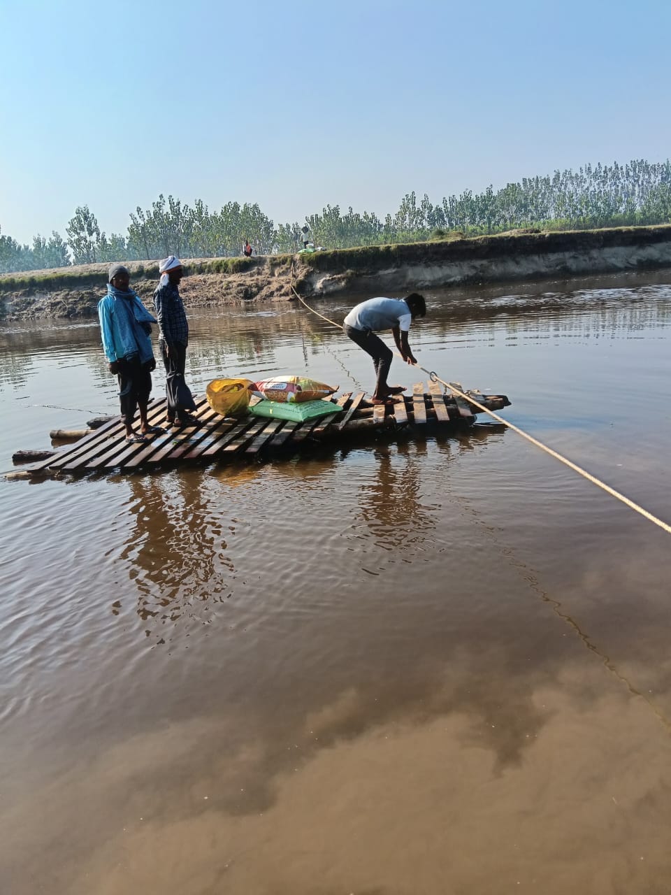 Villagers cross the river daily using tubes and wood.