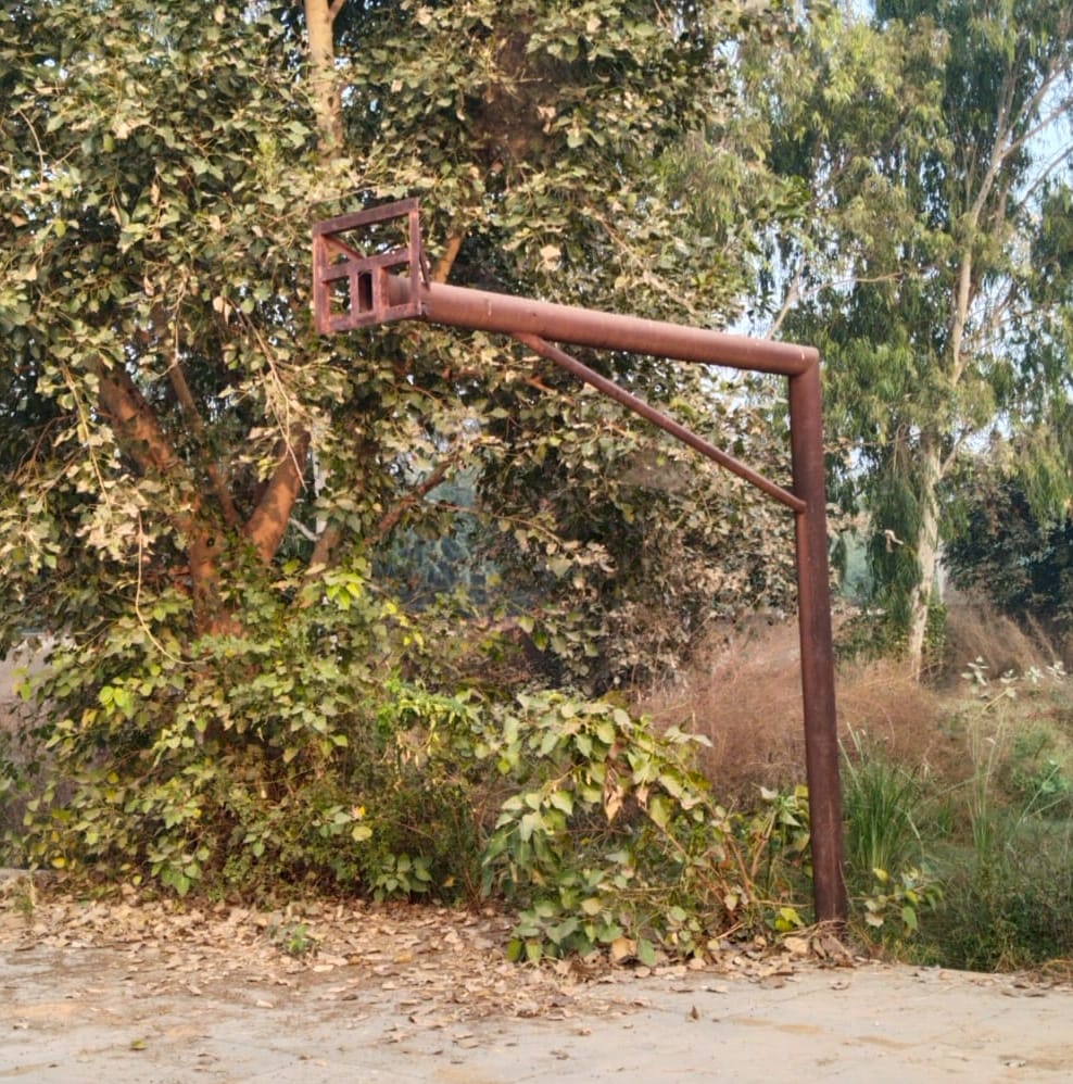 The basketball poles are rusted, and players spend their own money cleaning the field.