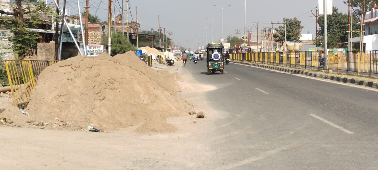 Piles of gravel on the side of the highway, straw being sold somewhere