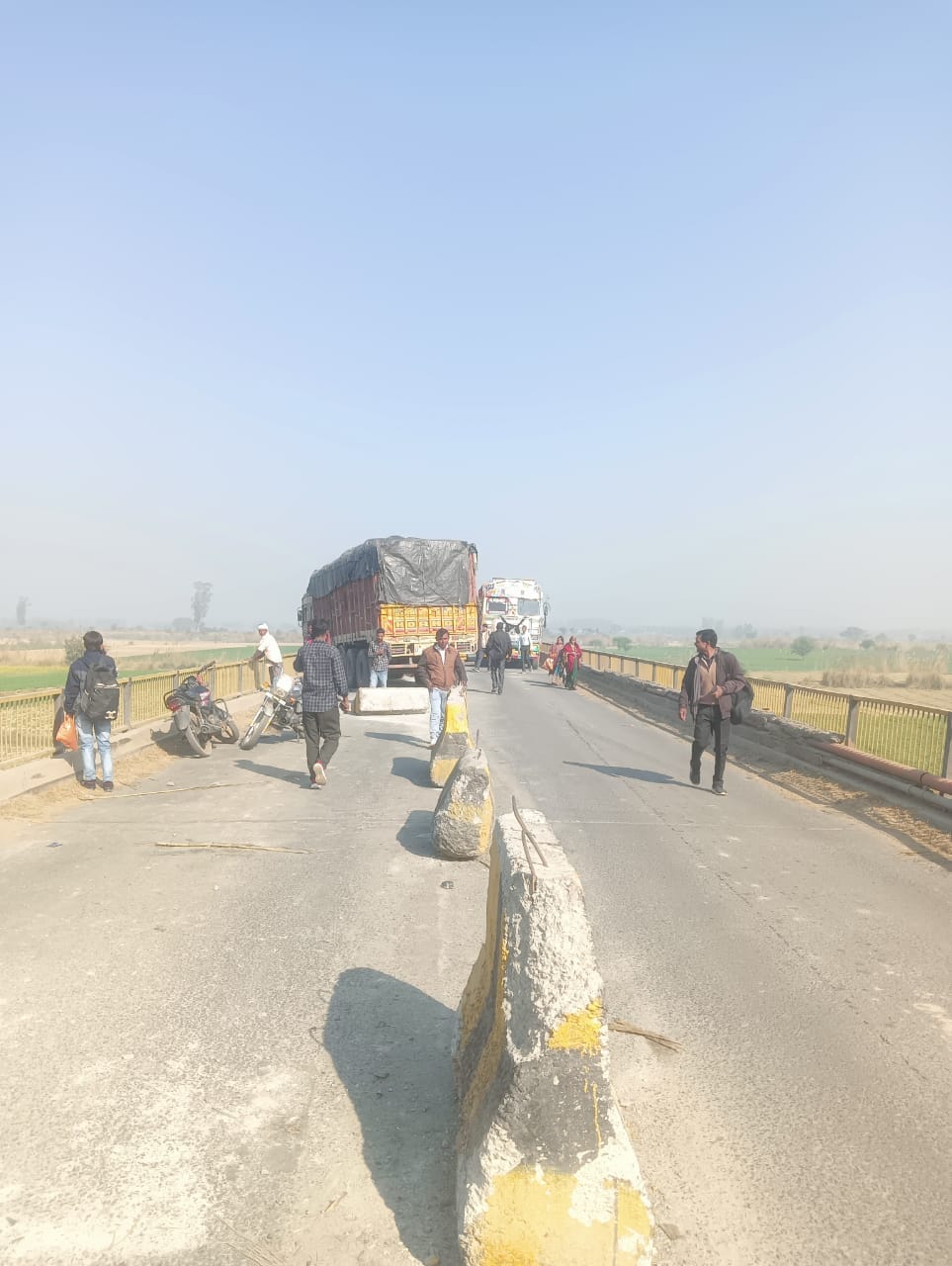 A truck loaded with maize broke the bridge divider and got stuck in the Ramganga river, causing a 15 km long traffic jam on the highway.