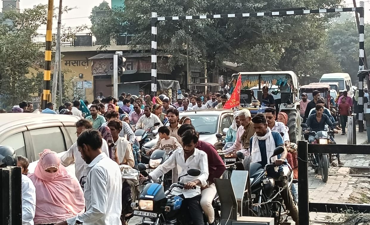 People are struggling in the jam at the railway crossing.