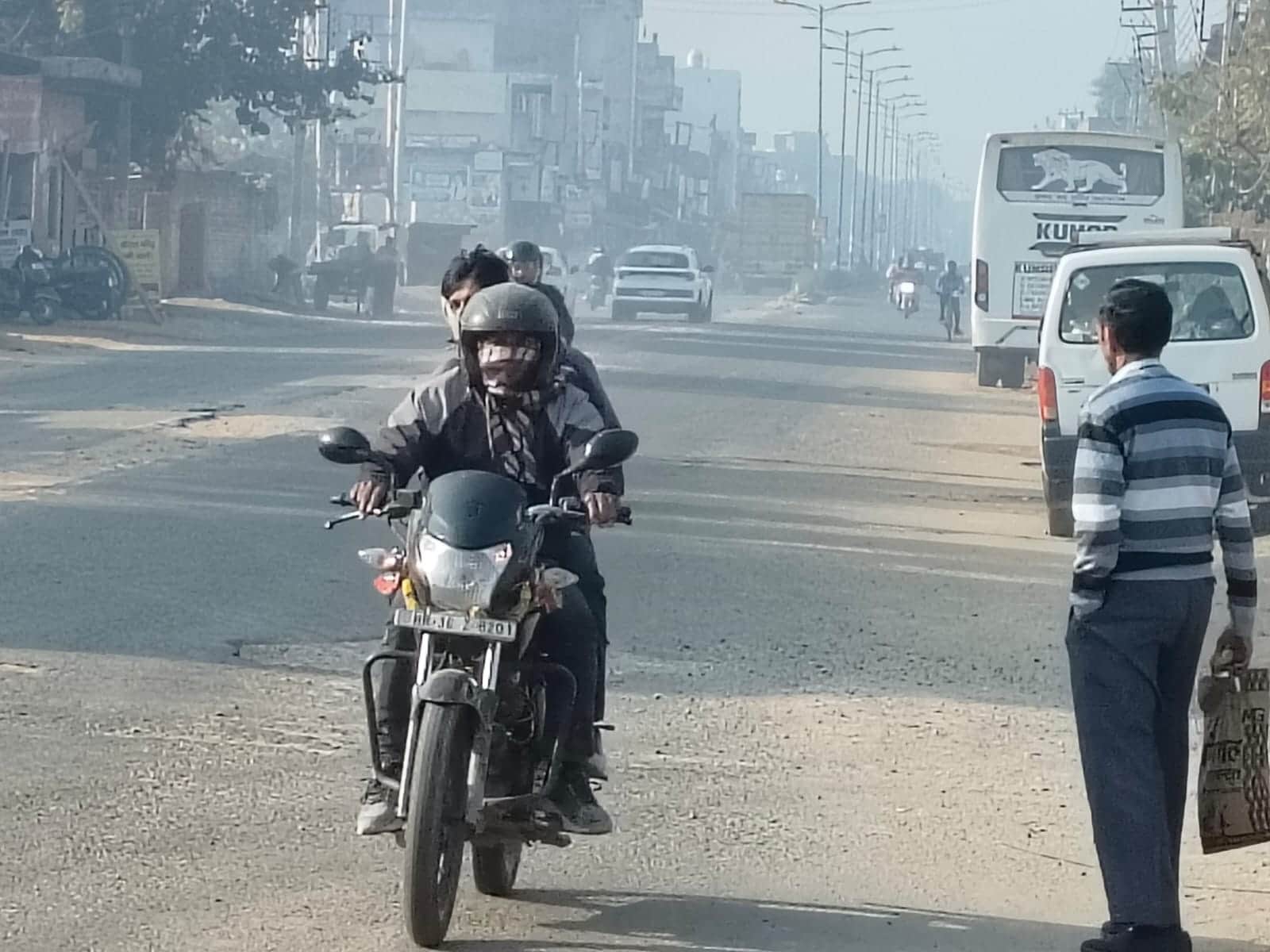 ठंड से बचने के लिए गर्म कपड़े पहनकर बाइक चलाता चालक। संवाद