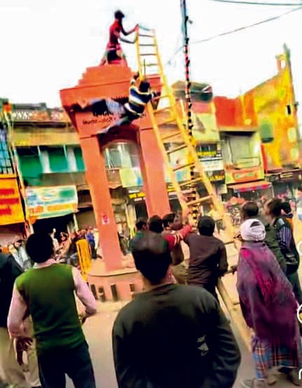 A maniac climbed onto the clock tower's dome and pushed down a young man who tried to rescue him.