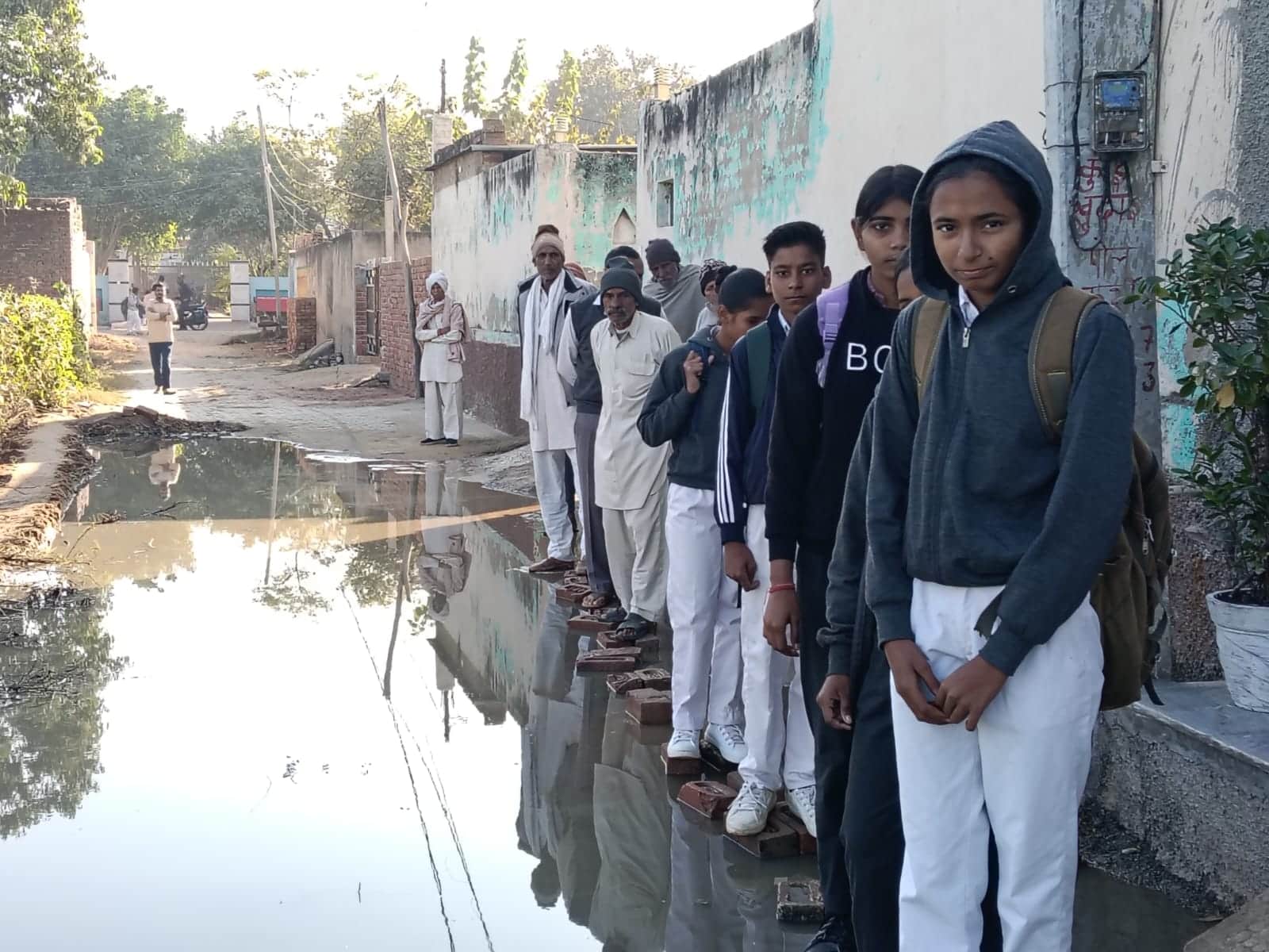 फोटो: 07रेवाड़ी। नैनसुखपुरा गांव स्थित राजकीय स्कूल के मुख्य रास्ते भरे पानी को दिखाते स्कूली