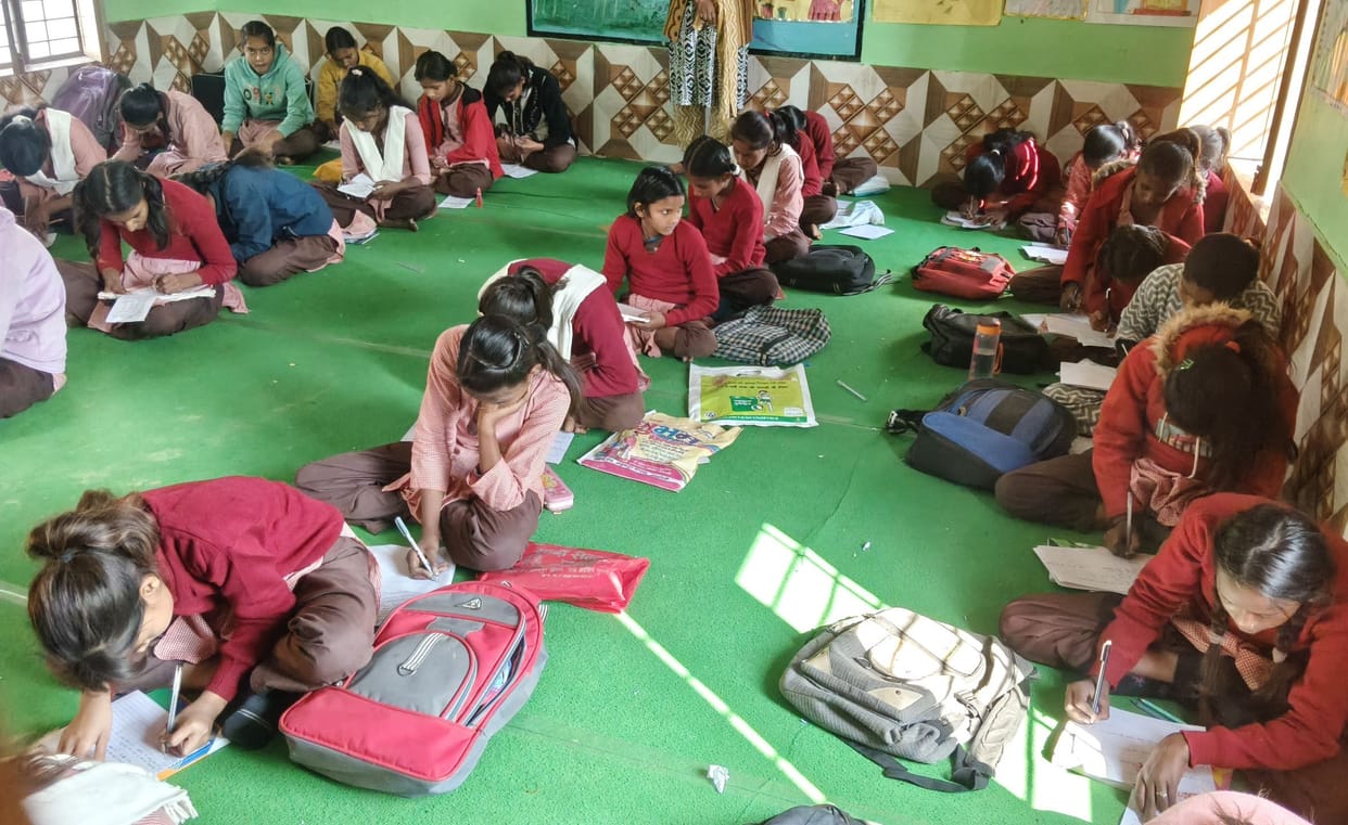 Children sat on mats in the cold and took their exams