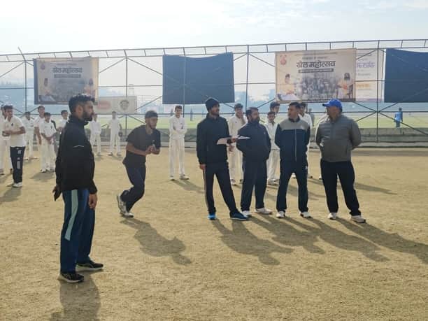 लुहणू मैदान में आयोजित क्रिकेट टीम ट्रायल में गेंद फेंकने जाता गेंदबाज और मौजूद चयनकर्ता। संवाद