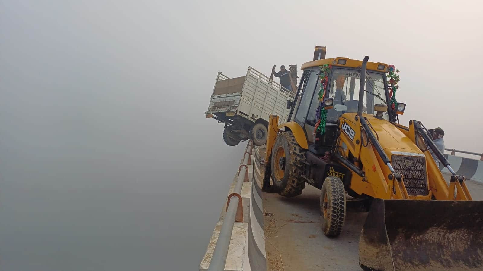 ट्रैक्टर से टक्कर के बाद धरम्मरपुर गंगा पुल की रेलिंग पर लटके पिकअप को क्रेन व जेसीबी मशीन से न