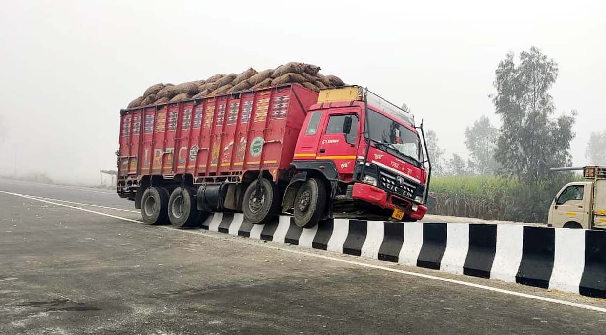 A DCM truck loaded with potatoes climbed onto the divider due to dense fog.